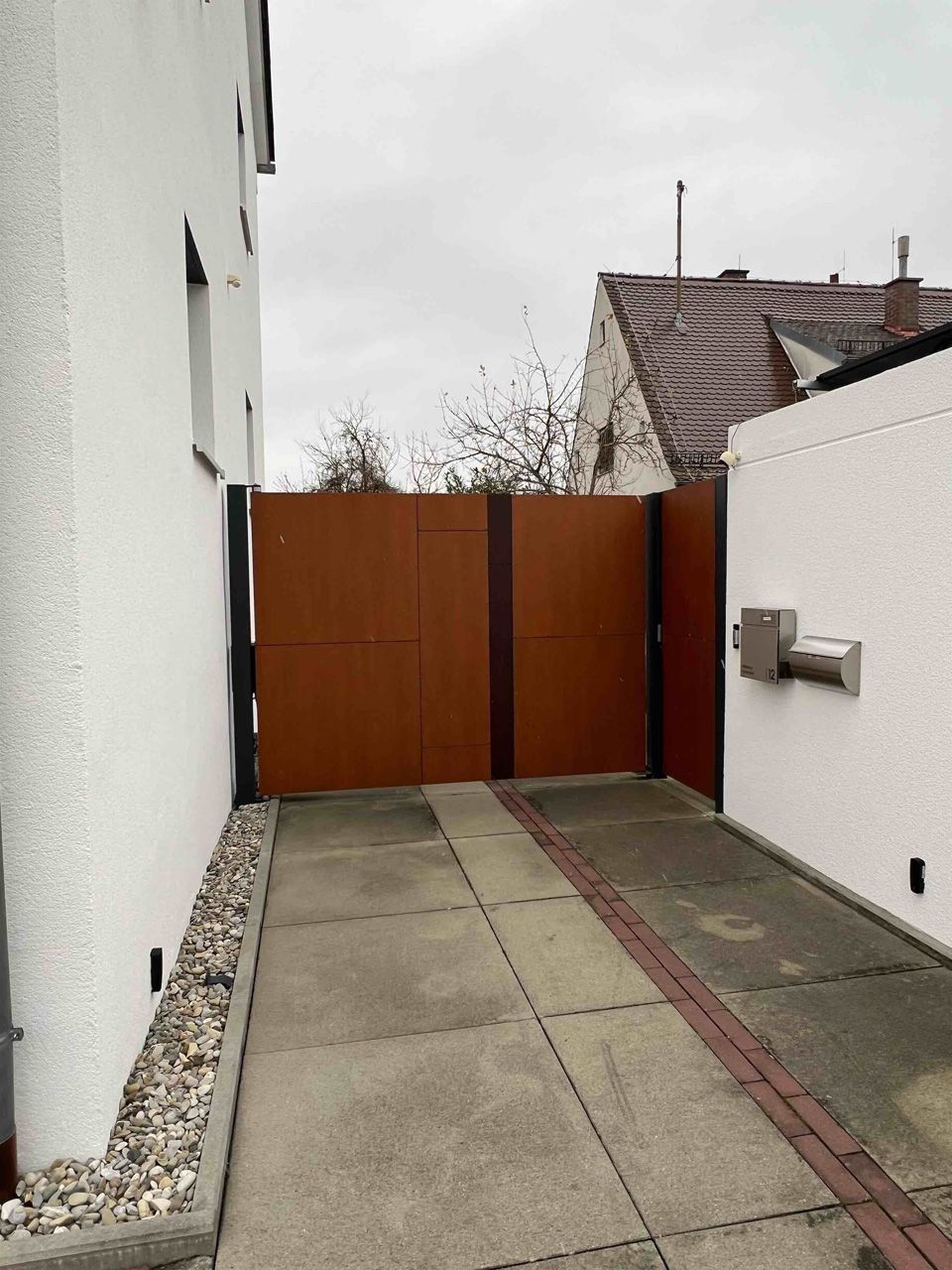 Ein weißes Gebäude mit einem braunen Zaun und einem Briefkasten