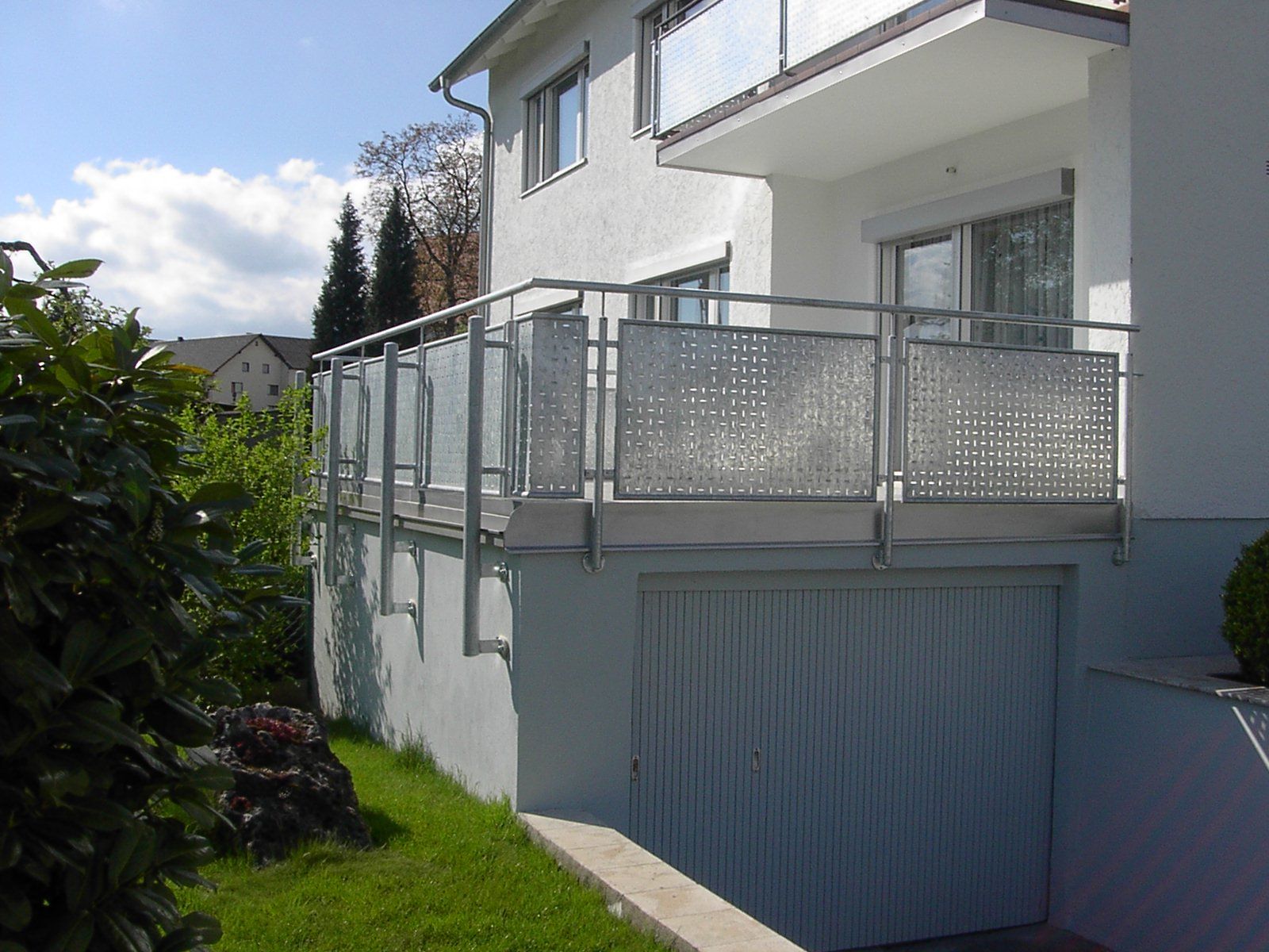 Ein weißes Haus mit Balkon und einer Garage darunter