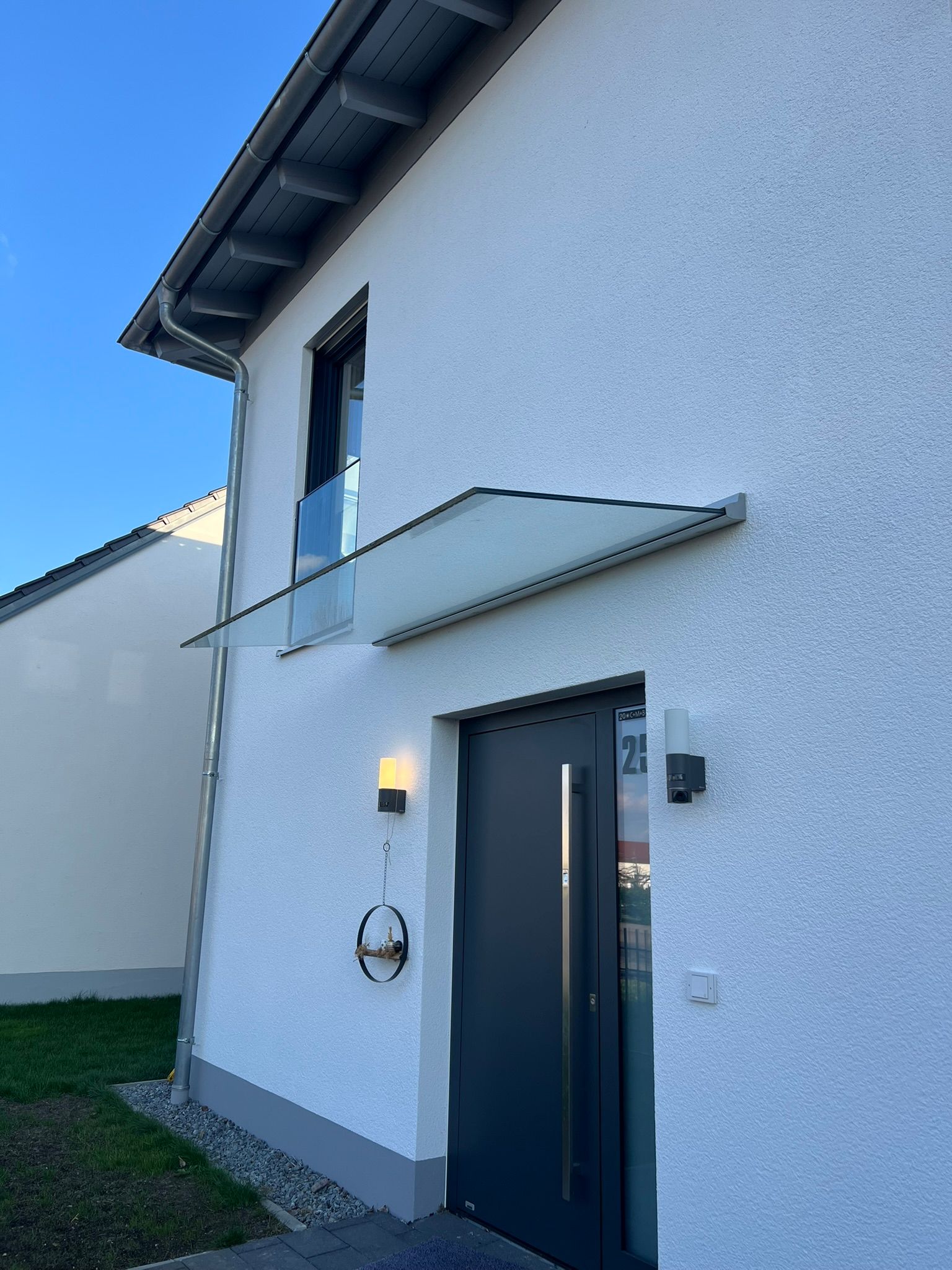 Ein weißes Haus mit einer schwarzen Tür und einem Glasdach