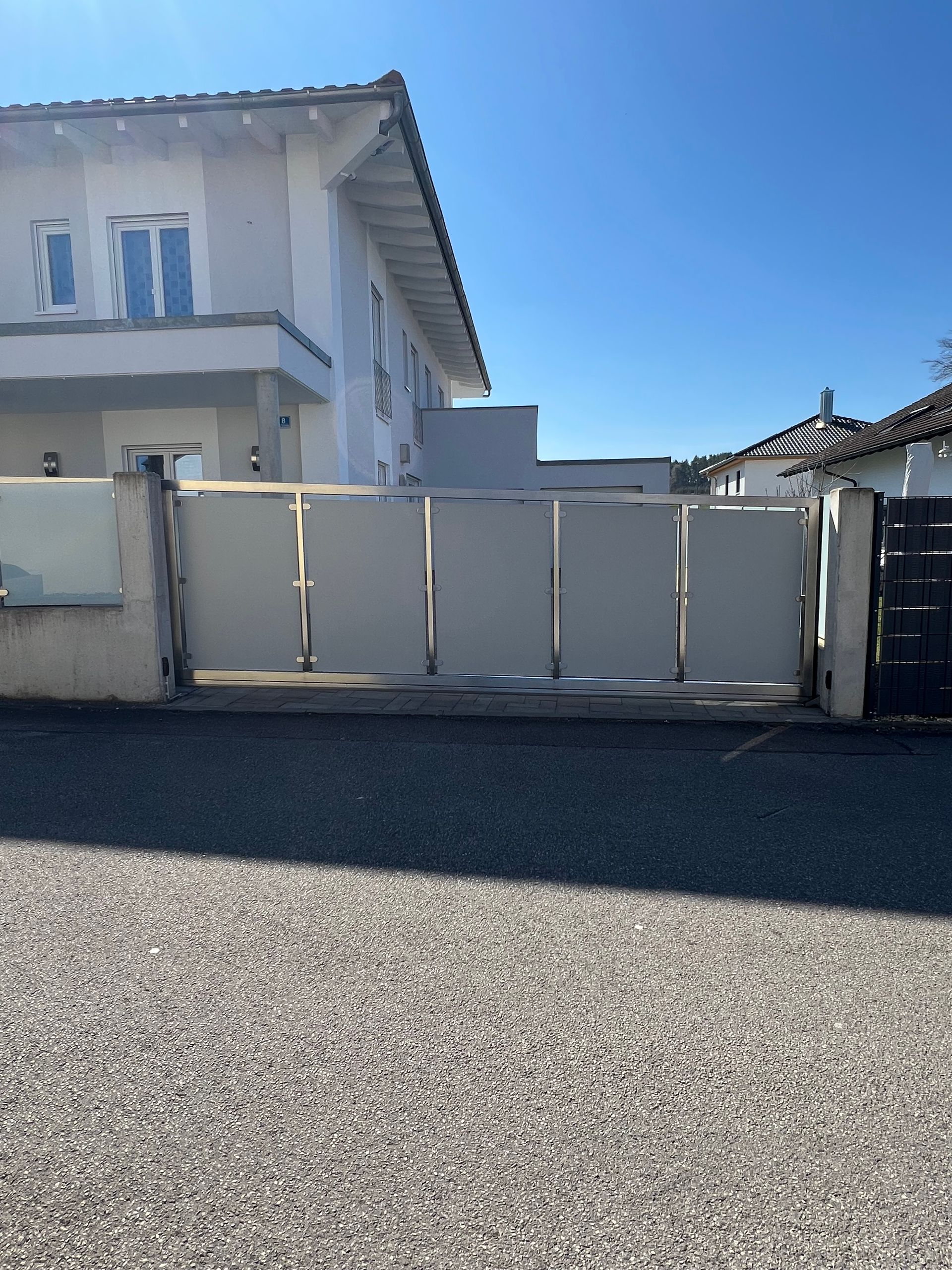 Ein weißes Haus mit einem Schiebetor davor