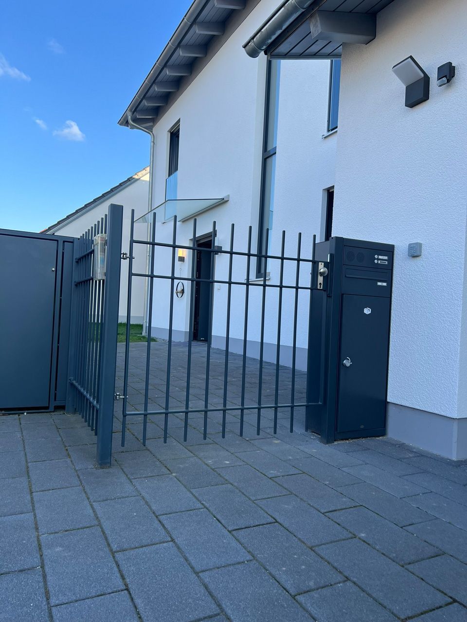 Ein weißes Gebäude mit einem schwarzen Tor und einem Briefkasten