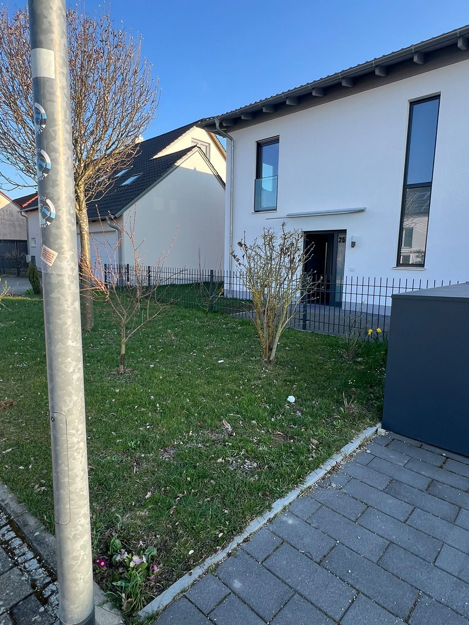 Ein weißes Haus mit einem Zaun und einem Baum davor.