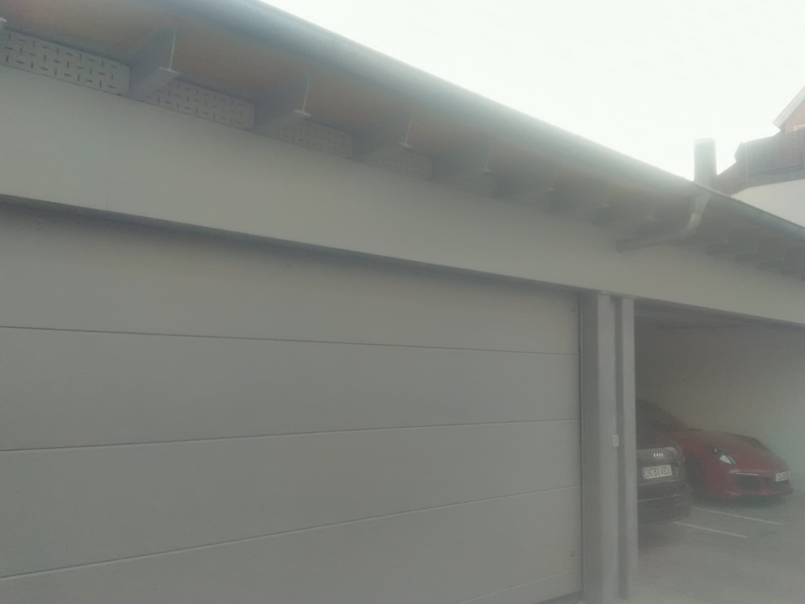 Ein Garagentor, unter dem ein Auto geparkt ist.