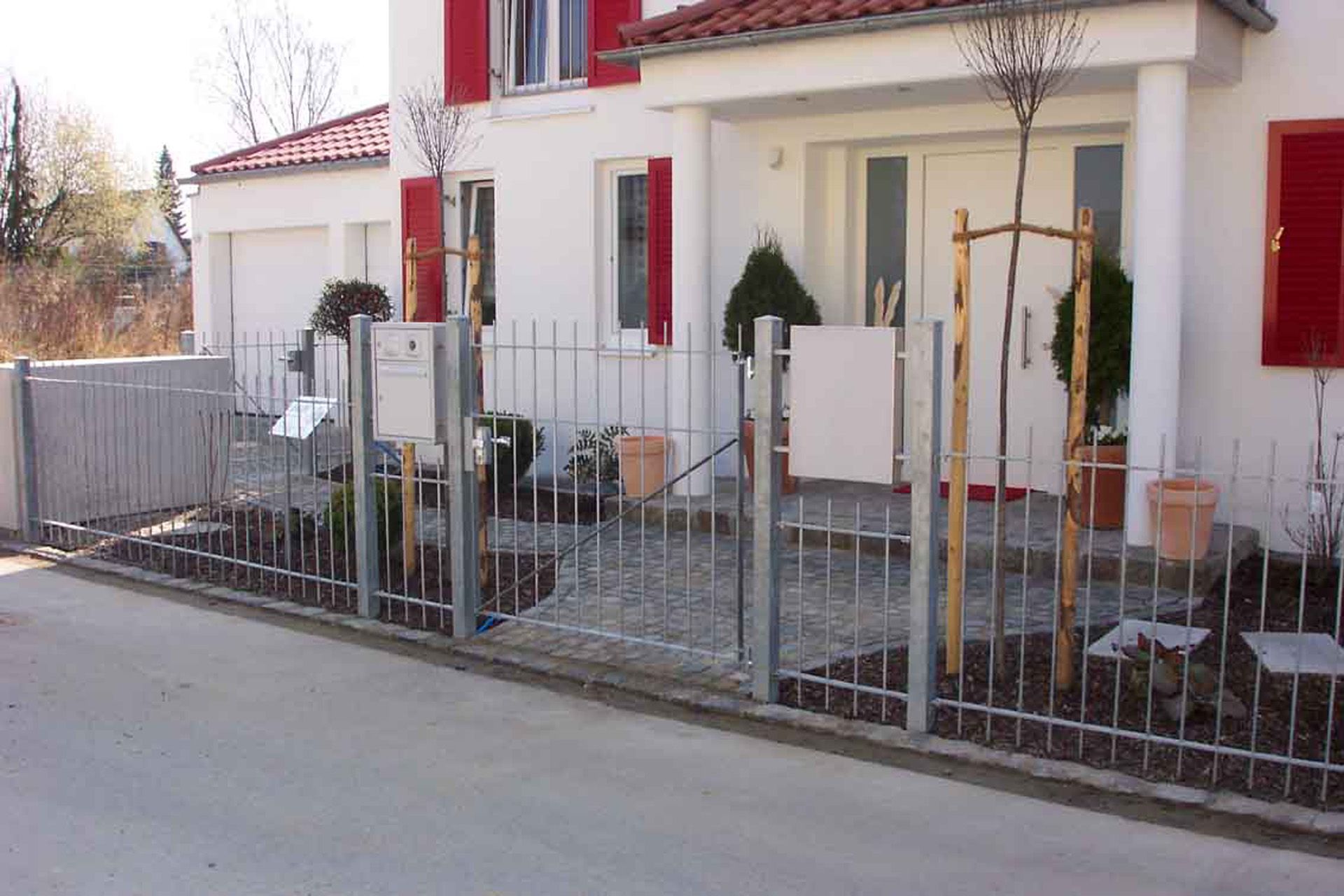 Ein weißes Haus mit einem Metallzaun davor