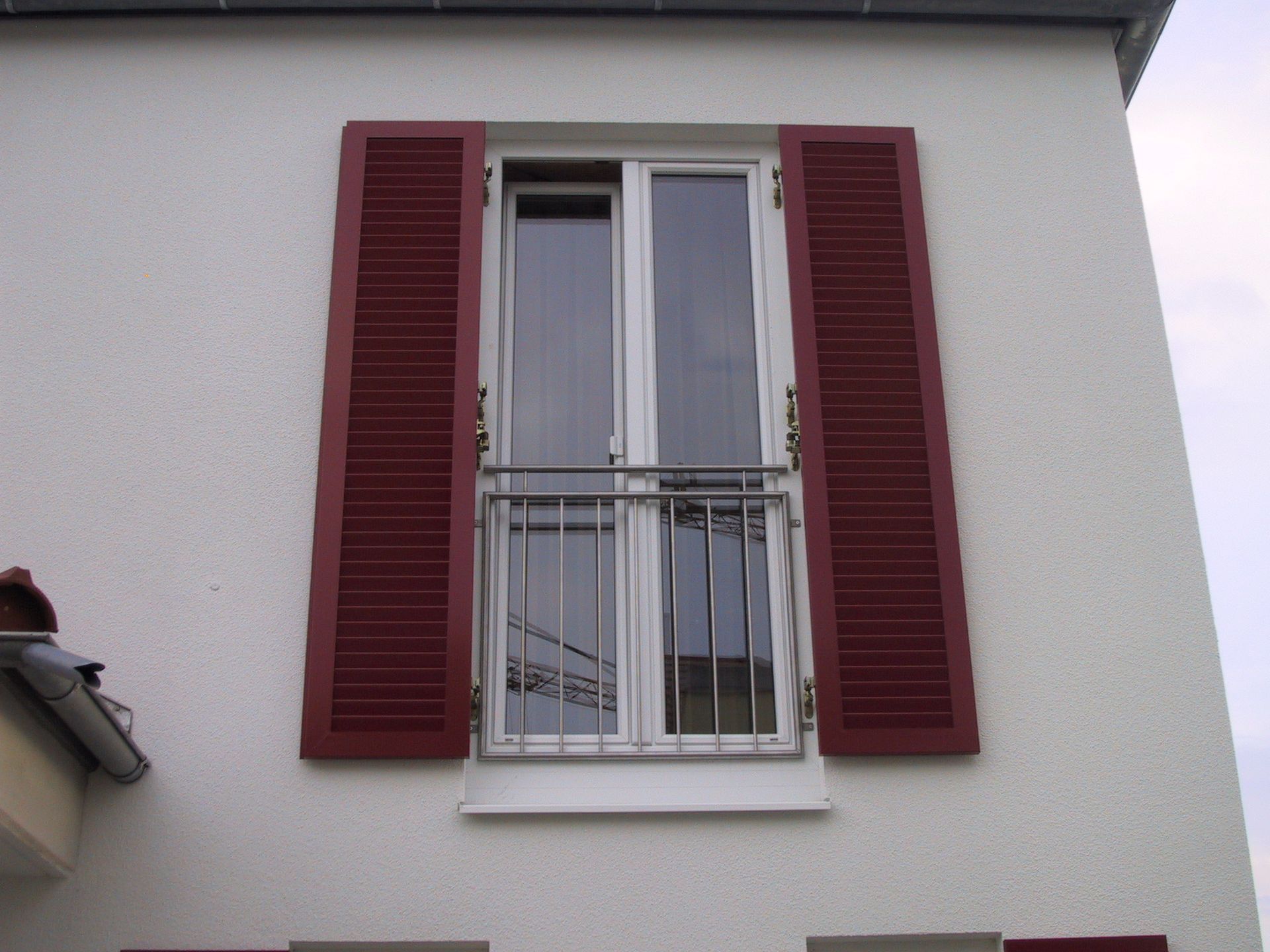 Ein Fenster mit roten Fensterläden an einem weißen Gebäude