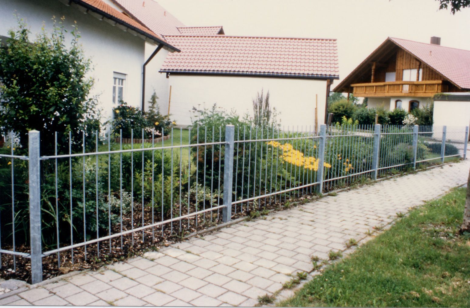 Ein Metallzaun umgibt einen Garten vor einem Haus