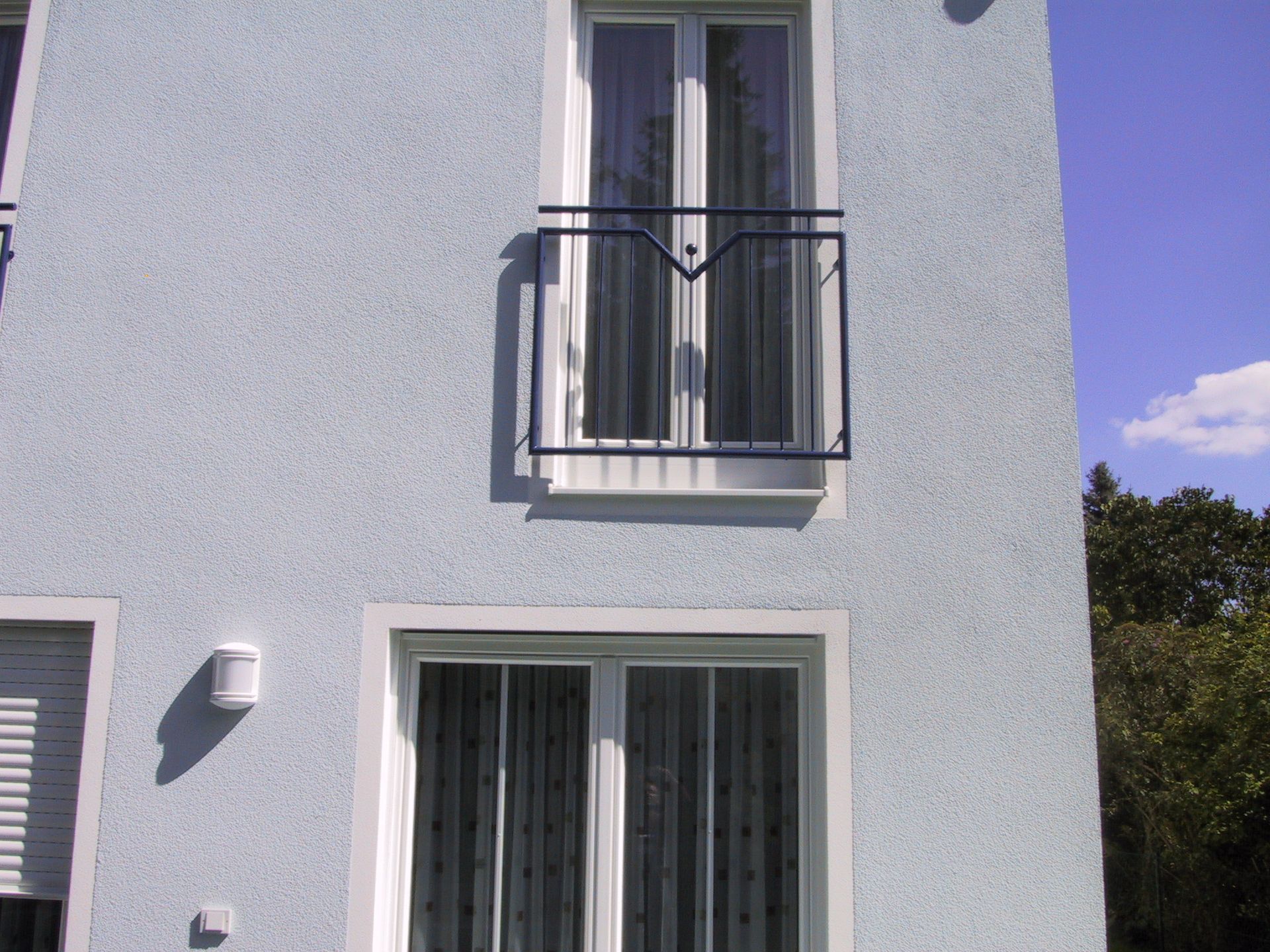 Ein blaues Gebäude mit weißen Fenstern und einem Balkon