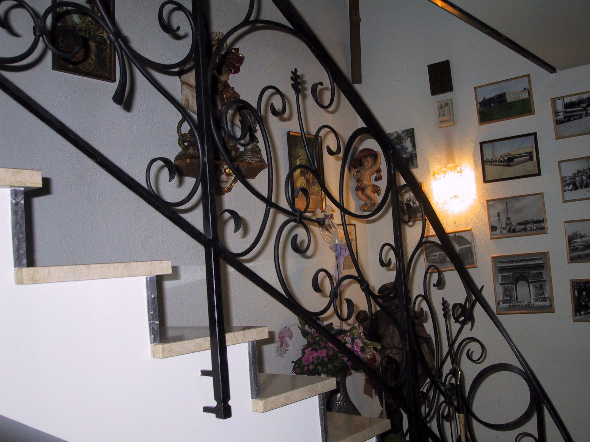 Eine Treppe mit schmiedeeisernem Geländer und Bildern an der Wand