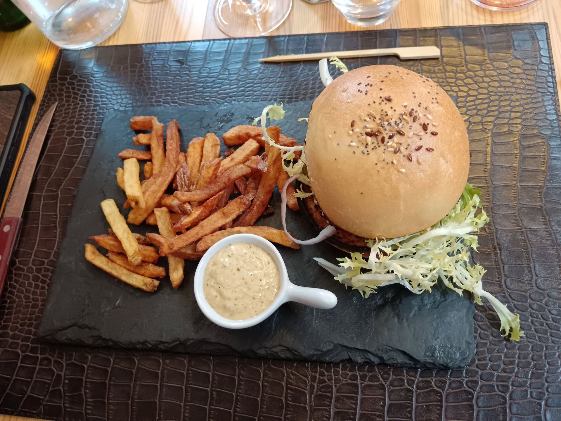 Hamburger, frites et sauce sur une assiette noire.