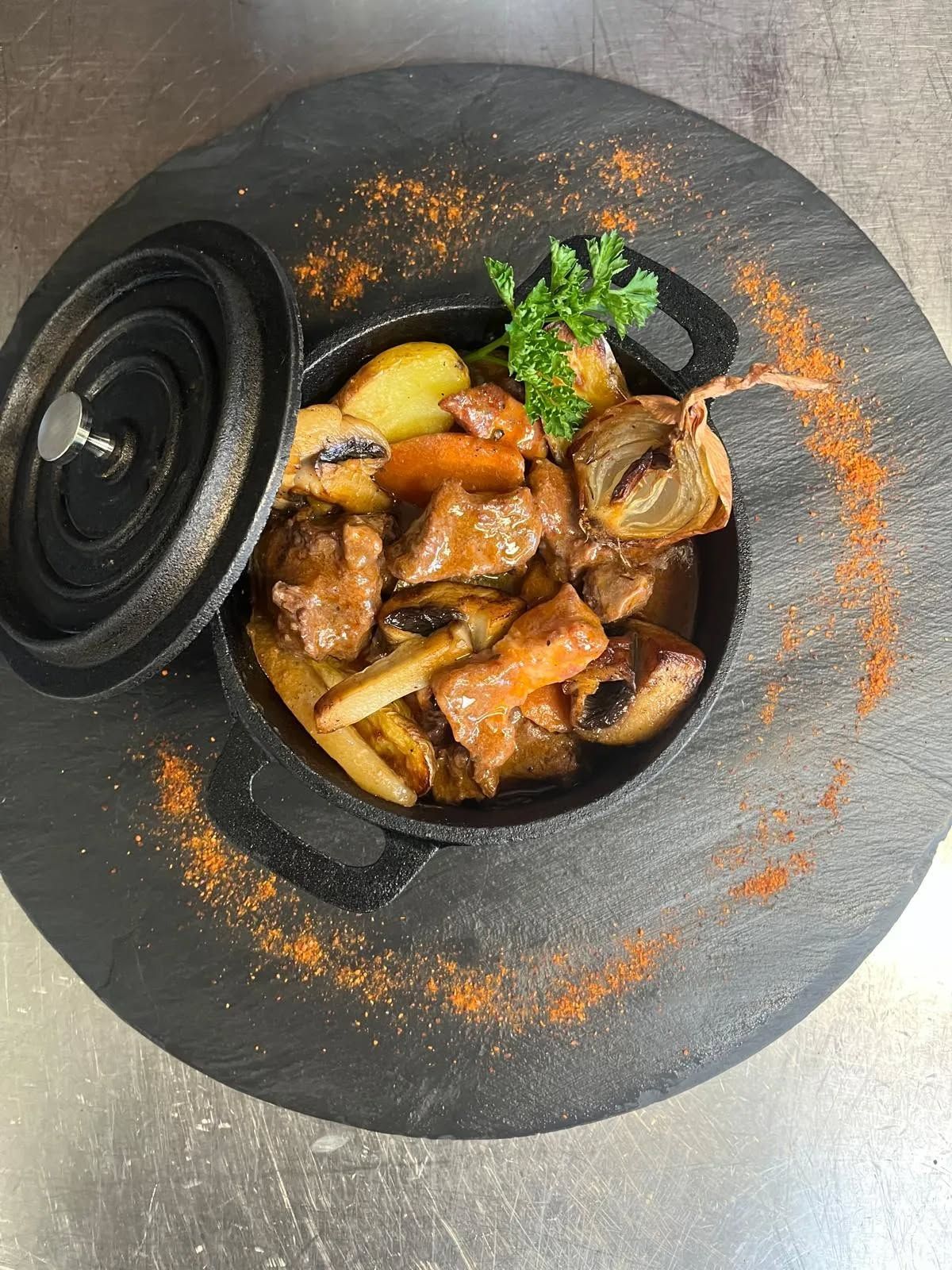 Cocotte en fonte noire avec de la viande et des légumes.