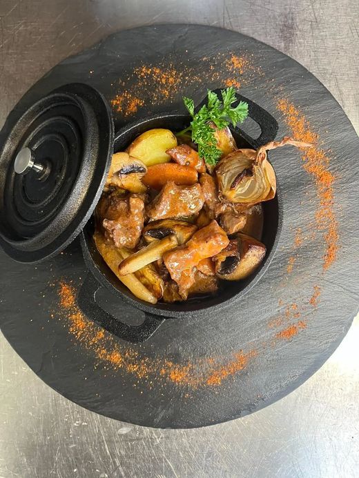 Marmite noire avec de la viande et divers légumes.