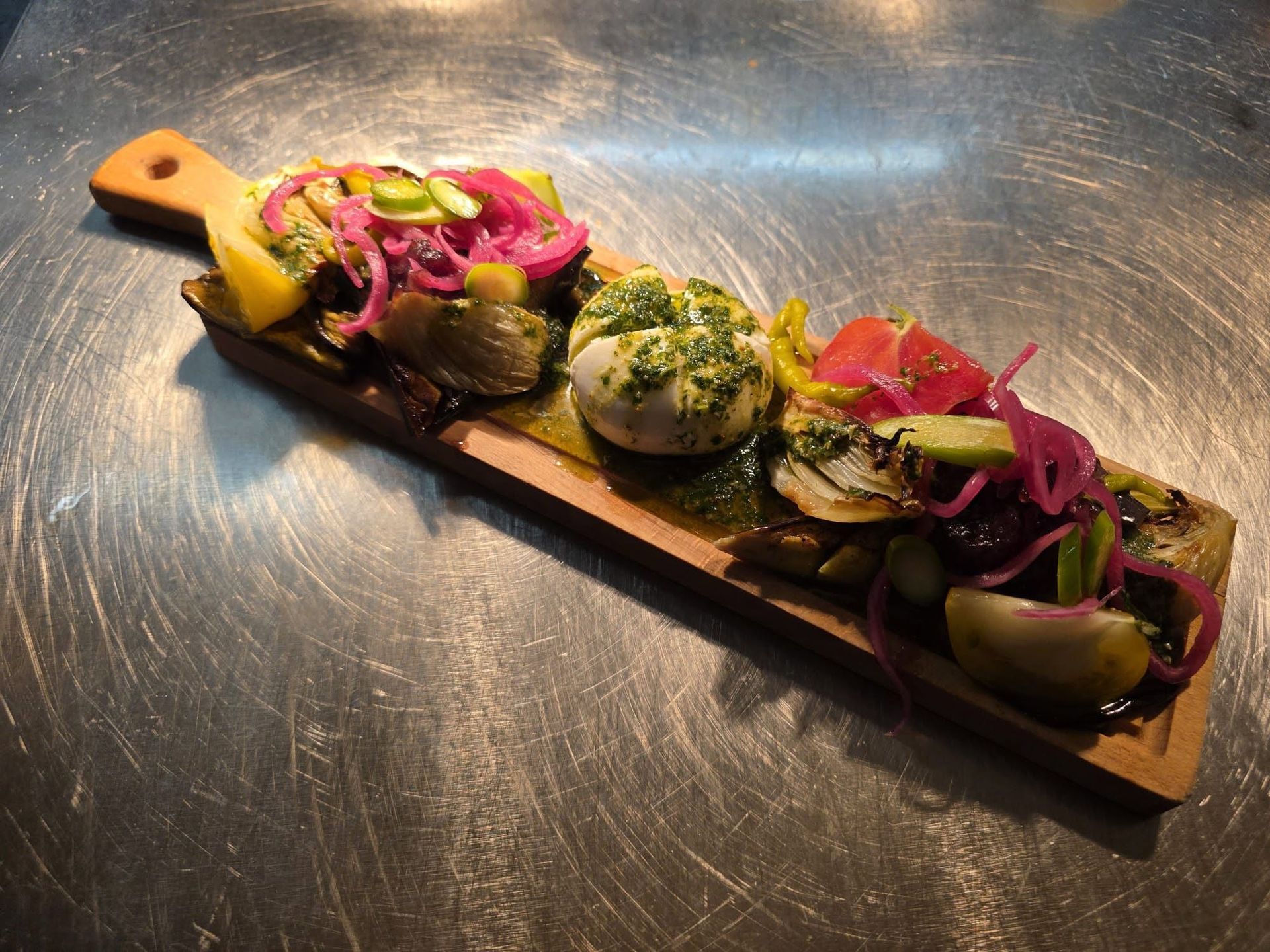 Planche apéritive composée de Burrata, légumes marinés et pesto.