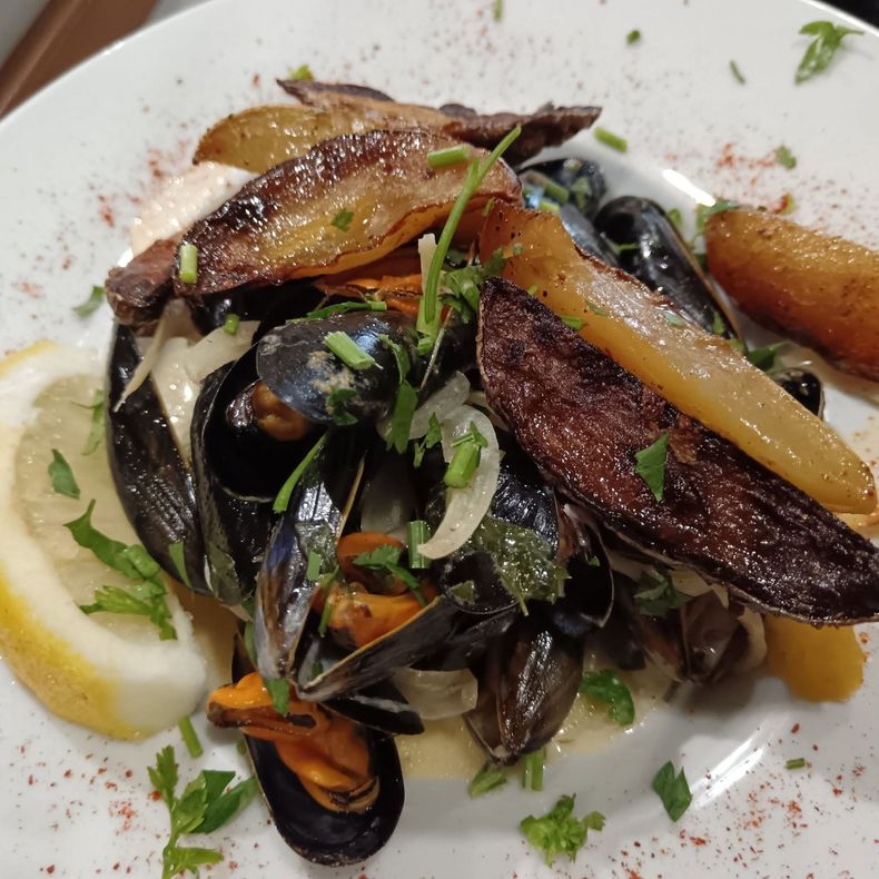 Moules servies dans une assiette blanche avec des légumes.