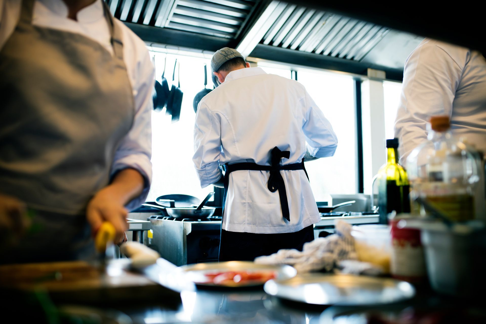 Des chefs préparent des plats dans la cuisine d'un restaurant.