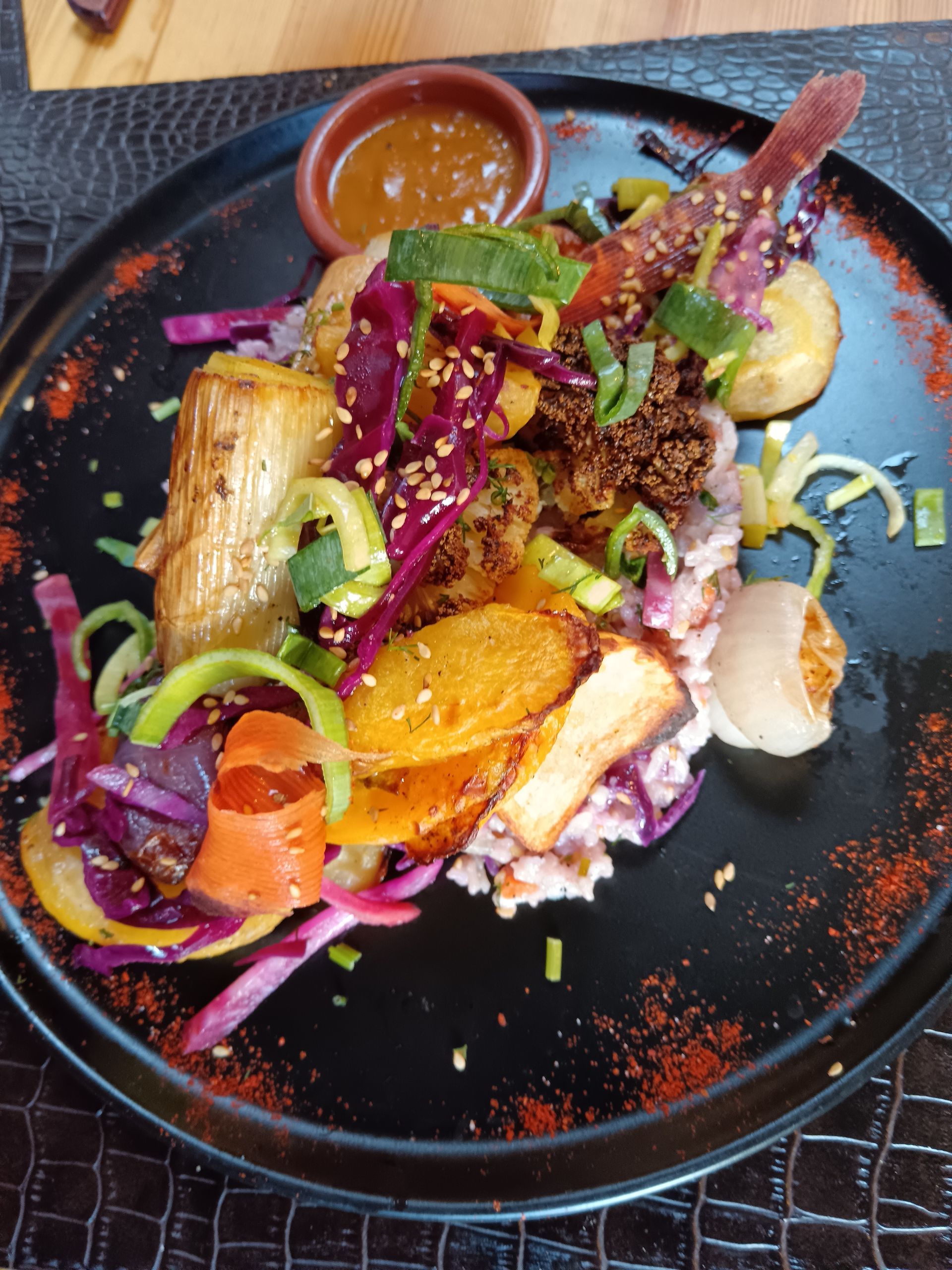 Salade gourmande colorée sur une assiette noire avec verdure, betteraves, agrumes et vinaigrette sur une table sombre