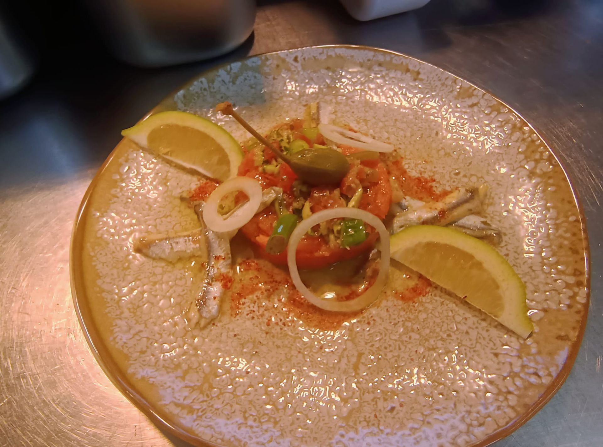 Assiette en verre avec une petite entrée garnie, des quartiers de citron et des légumes coupés en tranches sur une table