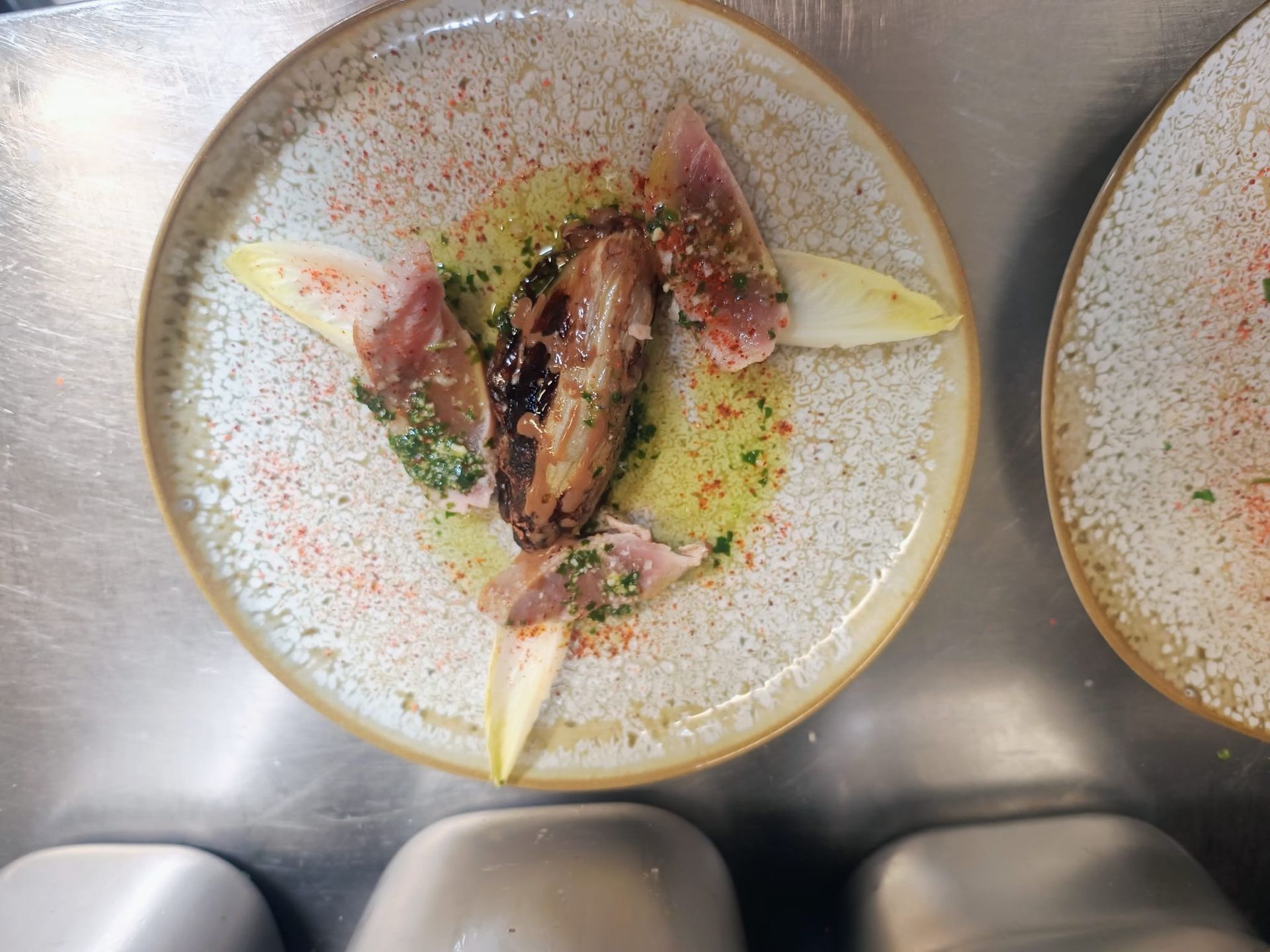 Plat de poisson avec sauce et quartiers de citron sur un comptoir en acier inoxydable