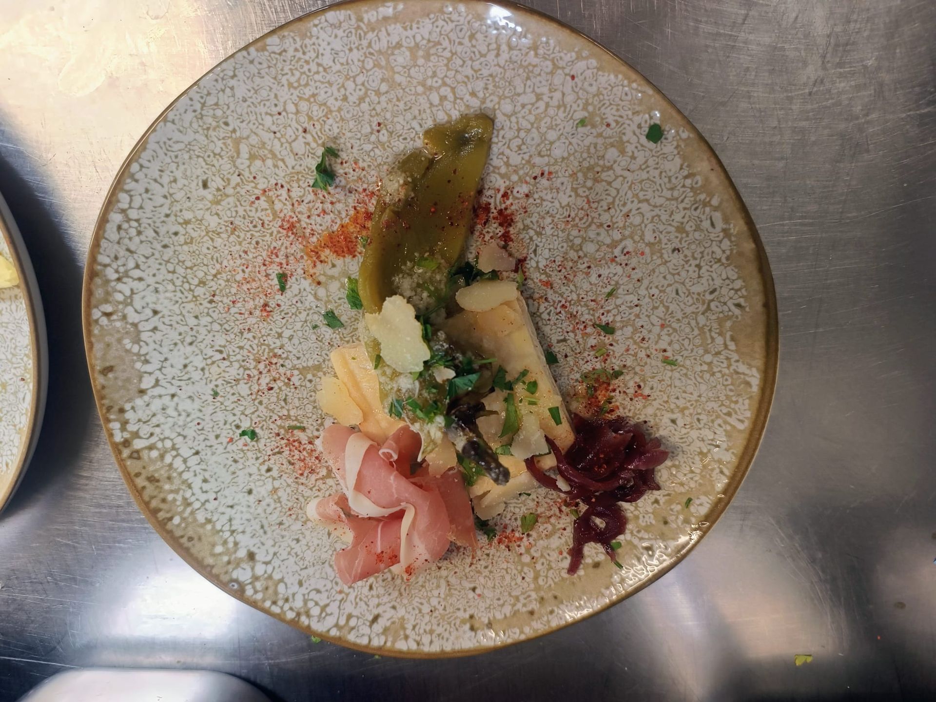 Plat gastronomique composé de viande tranchée, de légumes et de sauce, présenté sur une assiette en céramique mouchetée.
