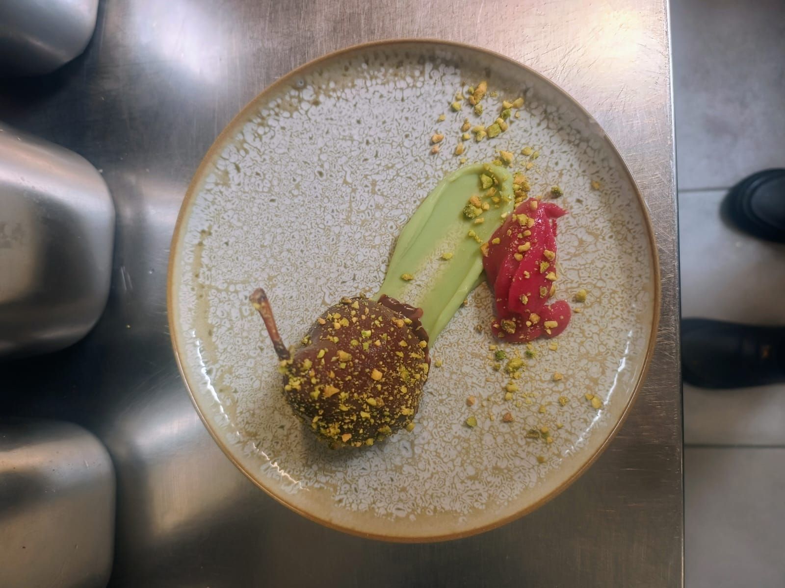 Assiette à dessert avec trois douceurs colorées et une garniture verte sur un comptoir de cuisine