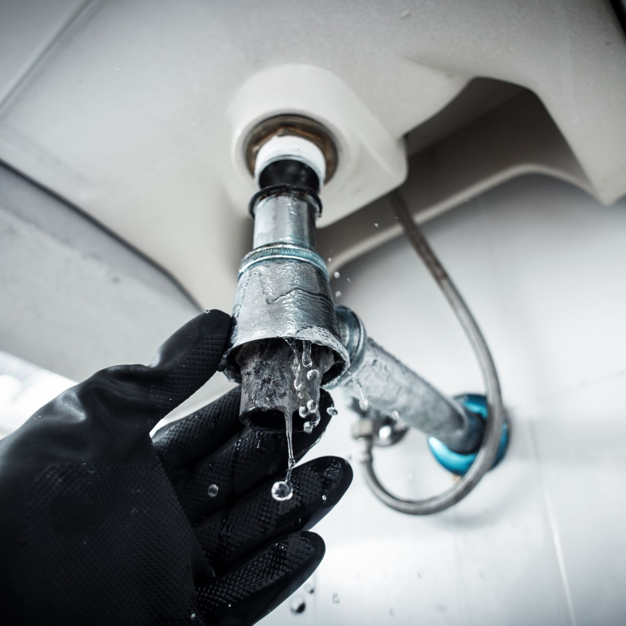 Un siphon de lavabo et un gant noir.