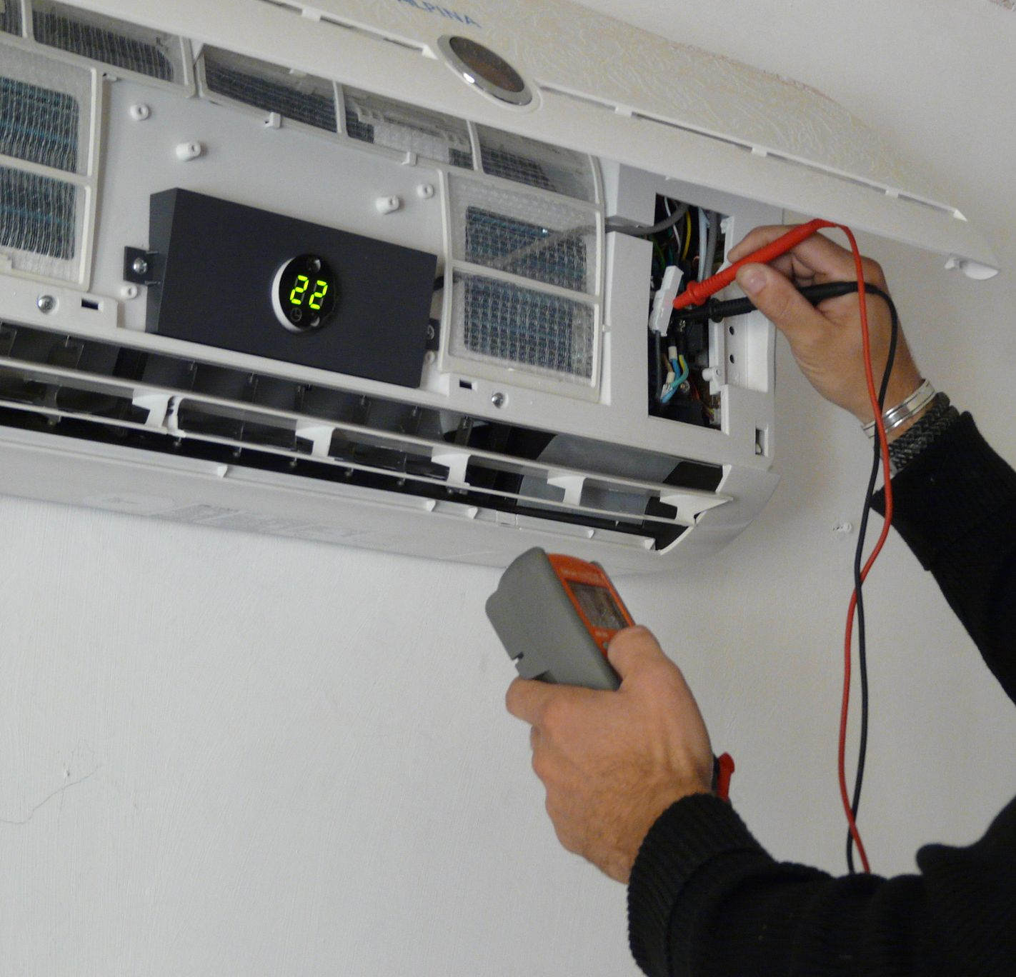 Un technicien mesure la tension d'un climatiseur.