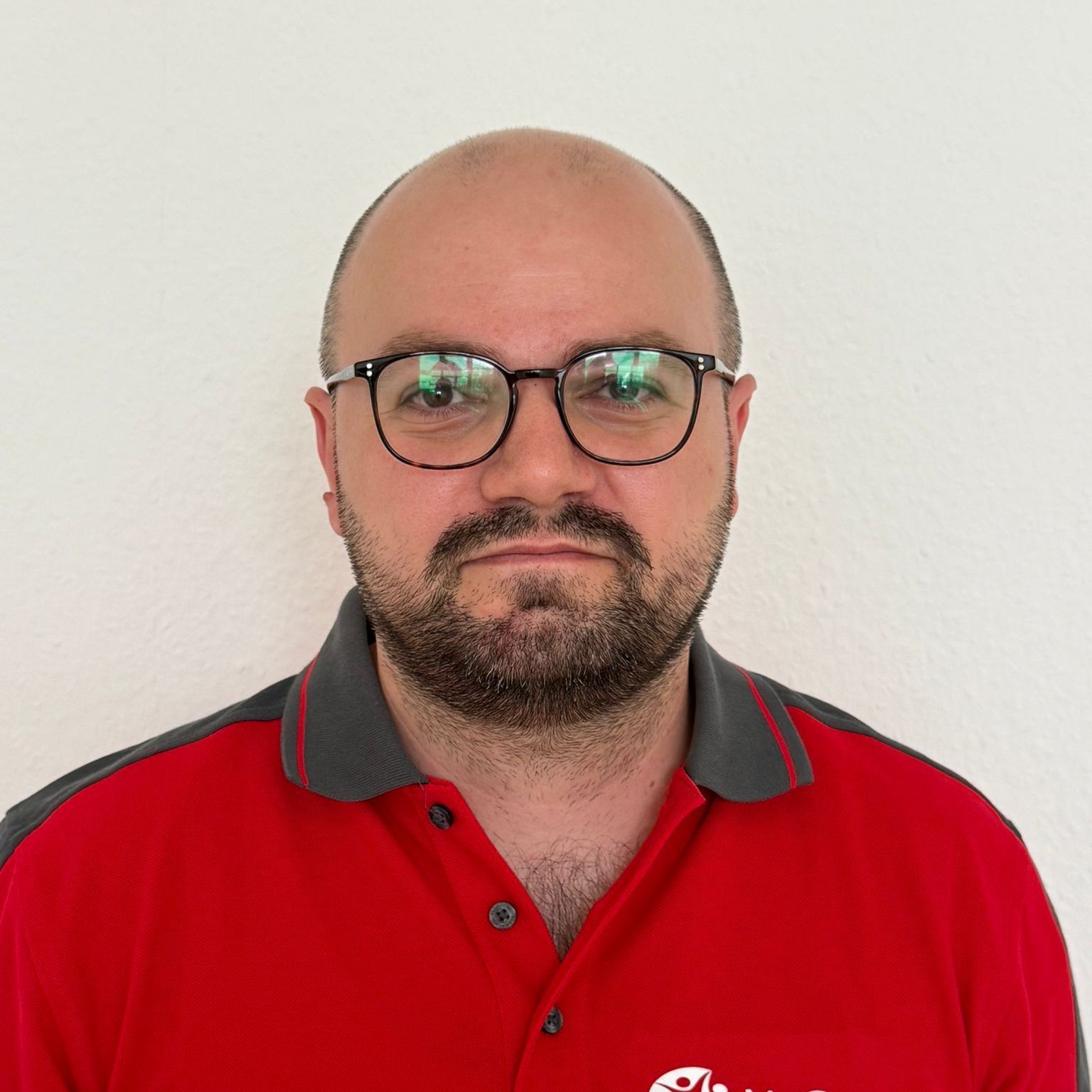 Ein Mann mit Brille und rotem Hemd lächelt in die Kamera