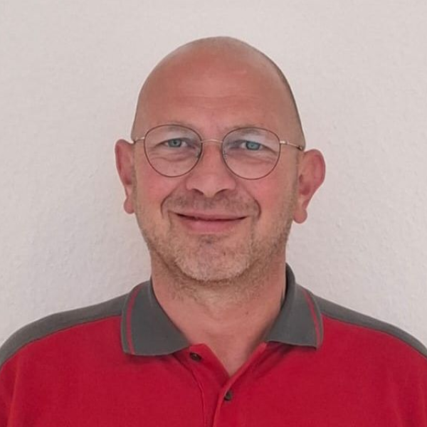 Ein Mann mit Brille und rotem Hemd steht in einem Kreis