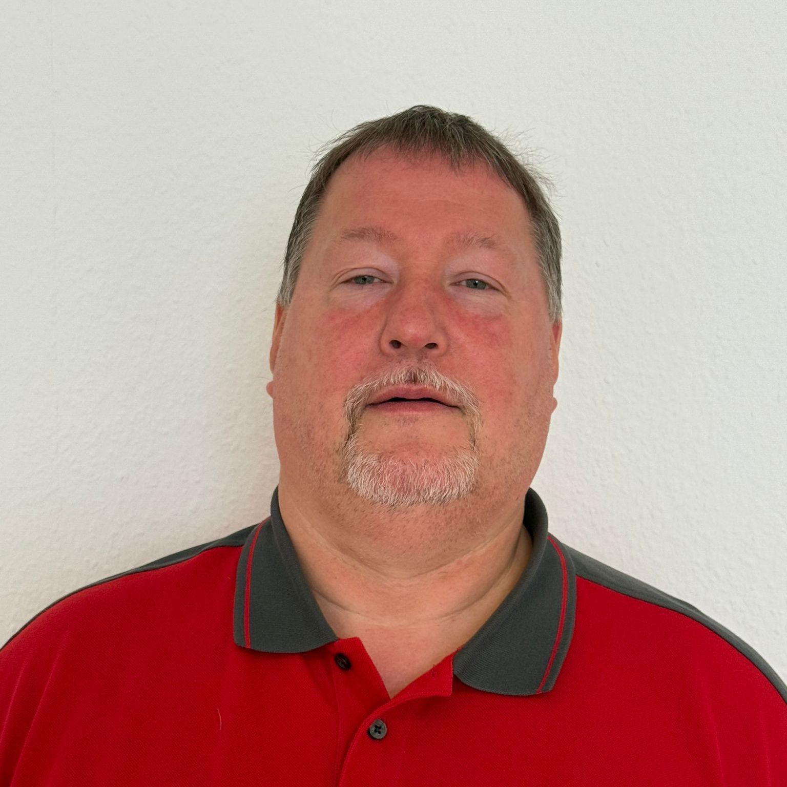 Ein Mann mit Brille und rotem Hemd lächelt in die Kamera