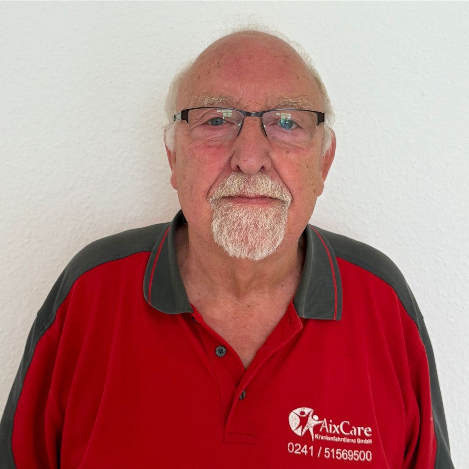 Ein Mann mit Bart trägt ein rotes Hemd mit der Aufschrift „Aircare“
