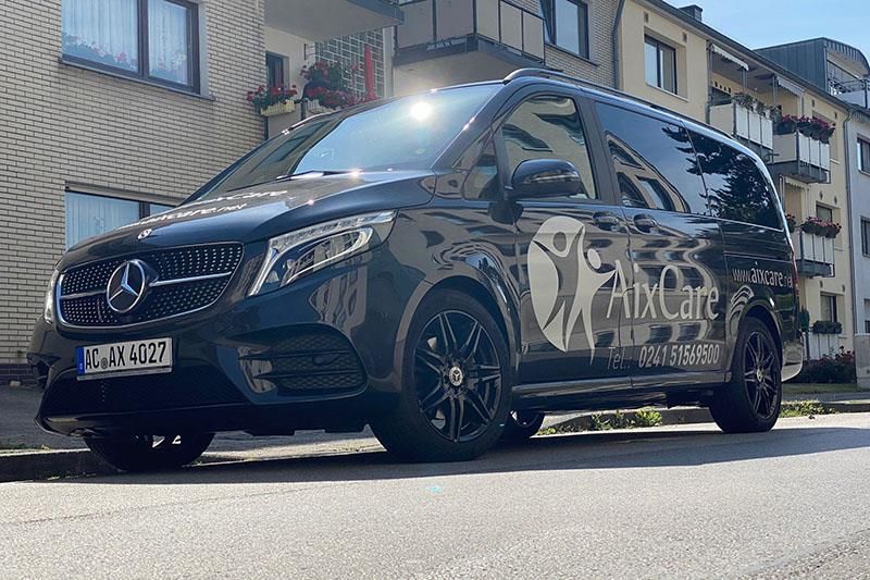 Ein schwarzer Mercedes-Van parkt vor einem Gebäude.