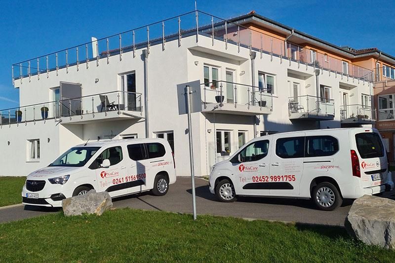 Zwei weiße Lieferwagen stehen vor einem großen weißen Gebäude