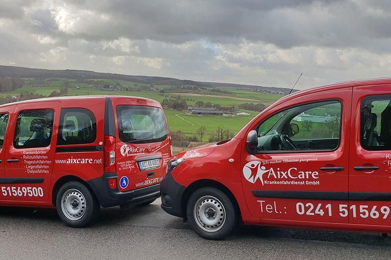 Zwei rote Aixcare-Transporter stehen nebeneinander