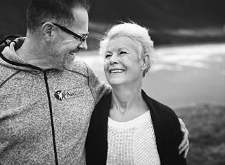 Auf einem Schwarzweißfoto stehen ein Mann und eine Frau nebeneinander und lächeln.