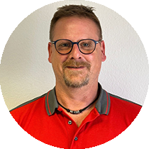 Ein Mann mit Brille und rotem Hemd steht in einem Kreis