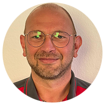 Ein Mann mit Brille und Bart lächelt in einem Kreis