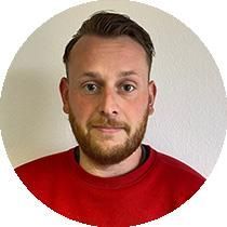 Ein Mann mit Bart trägt einen roten Pullover.