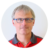 Ein Mann mit Brille und rotem Hemd steht in einem Kreis