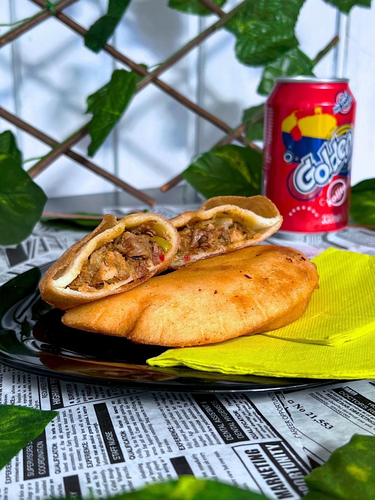 Un primer plano de un sándwich en un plato junto a una lata de refresco.