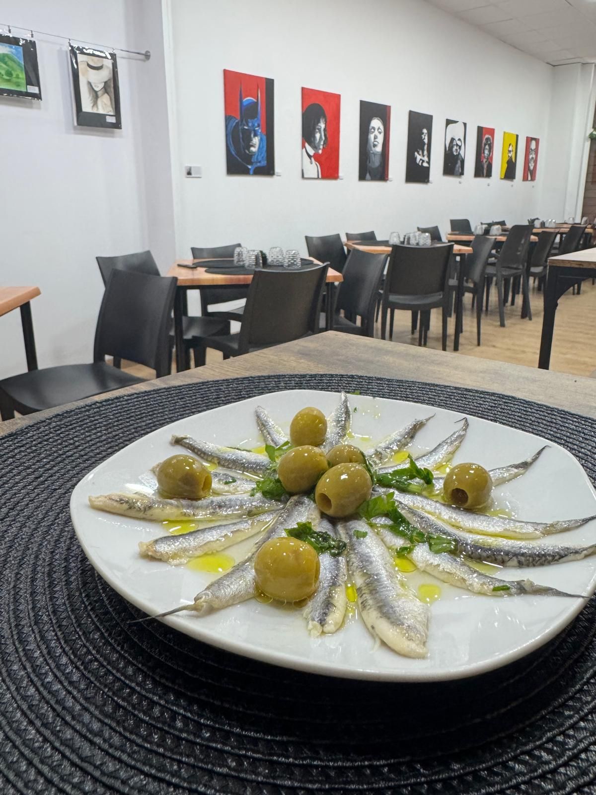 Un plato de comida con anchoas y aceitunas en una mesa de un restaurante.