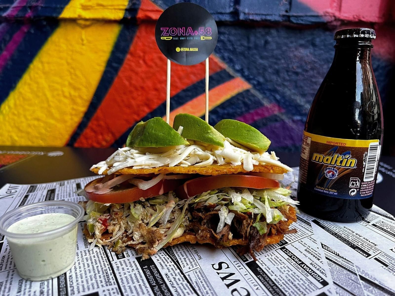 Un sándwich está sobre una mesa al lado de una botella de cerveza.