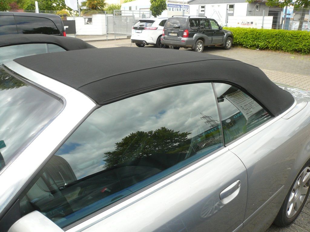 Ein silbernes Cabrio mit schwarzem Verdeck steht auf einem Parkplatz