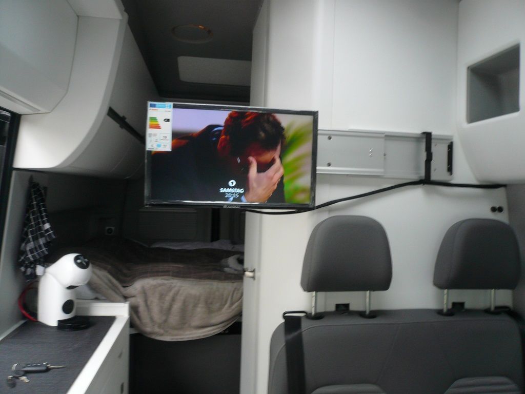 Ein Flachbildfernseher ist über einem Bett in einem Van montiert
