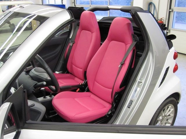 Ein weißes Auto mit rosa Sitzen steht in einer Garage