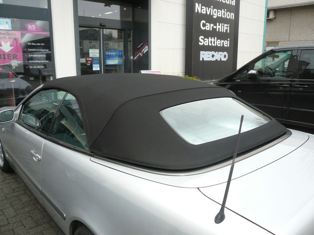 Ein silbernes Auto mit schwarzem Dach steht vor einem Schild mit der Aufschrift „Navigation“