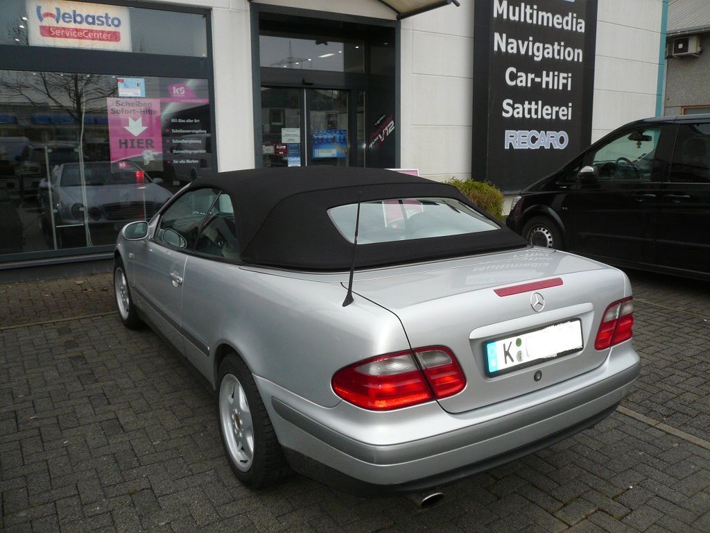 Ein silbernes Cabriolet steht vor einem Gebäude mit der Aufschrift „Multimedia-Navigation“