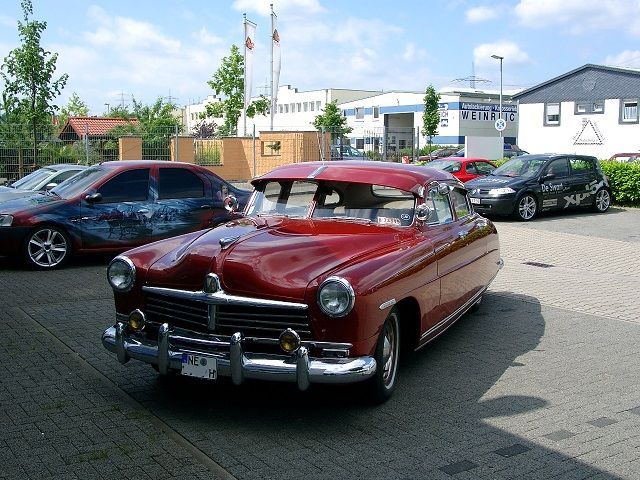 Ein rotes Auto steht auf einem Parkplatz mit anderen Autos
