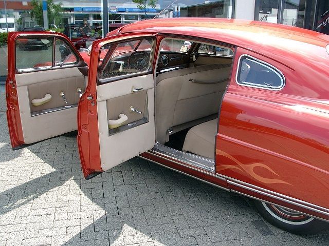 Ein rotes Auto mit offenen Türen steht am Straßenrand