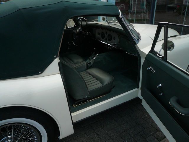 Ein weiß-grünes Cabrio mit offener Tür