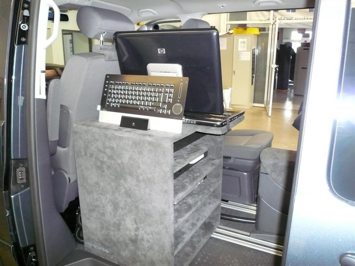 Ein Laptop und eine Tastatur stehen auf einem Regal im hinteren Teil eines Lieferwagens