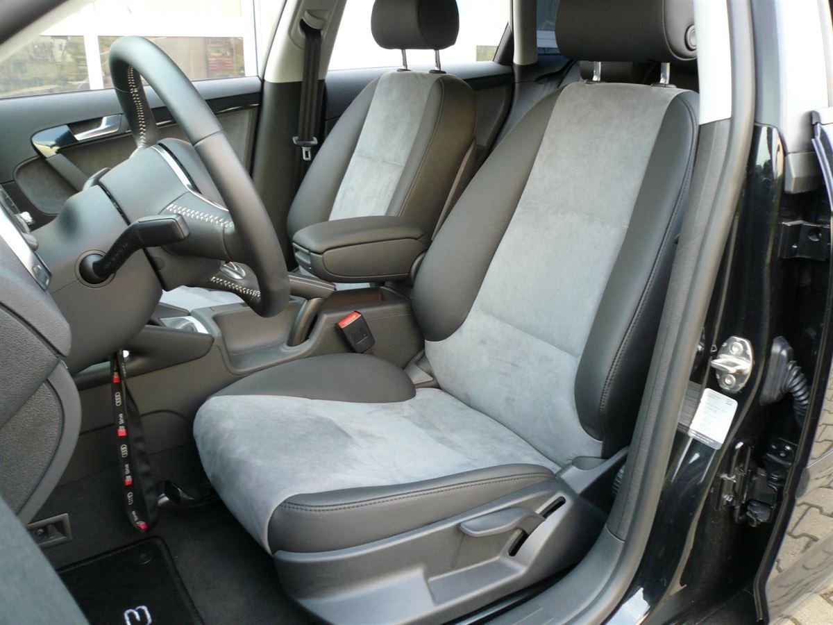 Der Innenraum eines schwarzen Autos mit grauen Sitzen und einem Lenkrad